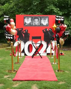 a red carpet on the ground in front of a stage with balloons and pictures behind it