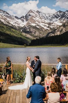 a bride and groom standing at the end of their wedding ceremony in front of mountains