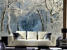 a white couch sitting in front of a window covered in frosty trees and snow