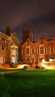 an old building lit up at night with green grass