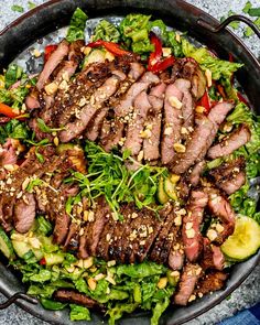 a large bowl filled with meat and veggies on top of a blue table cloth