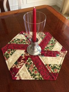 a red candle sits on top of a quilted coaster