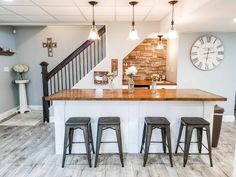 a kitchen with three stools and an island in the middle, under a stair case