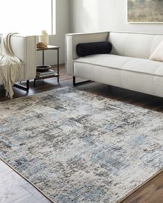 a living room with a couch, rug and painting on the wall in front of it