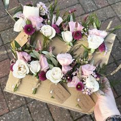 a person holding flowers on top of a piece of brown paper with tags attached to it