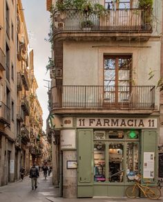 people walking down the street in front of an old building with balconies on it