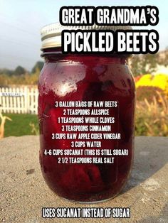 a jar filled with pickled beets sitting on top of a cement slab next to a white picket fence