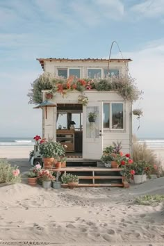 a small white house on the beach with potted plants