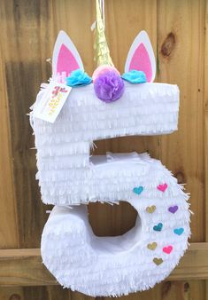 a white cake shaped like the number five with a unicorn's horn on top