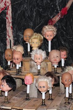 many dolls are placed on wooden boards with candles in front of them and blood dripping from the wall behind them