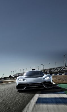 a white sports car driving on a race track with blue sky in the back ground