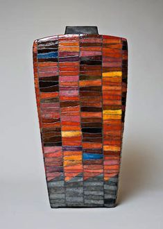 a vase made out of multicolored tiles on a white surface with no one in it