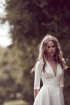 a woman in a white dress is standing outside