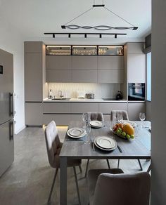 a dining room table and chairs with plates on it in front of an open kitchen