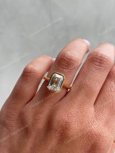 a woman's hand with a ring on it and an emerald stone in the middle