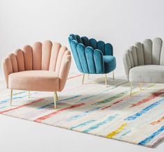 three chairs sitting on top of a rug next to each other in front of a white wall