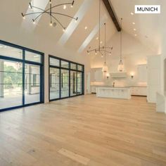 an empty living room with wood floors and large glass doors that lead into the kitchen