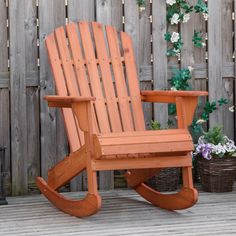 a wooden rocking chair sitting on top of a wooden deck next to a potted plant