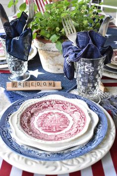 a patriotic table setting with plates, silverware and flowers