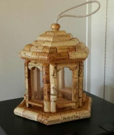 a small house made out of wine corks sitting on top of a black table