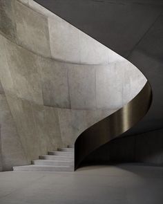 a curved metal staircase in front of a concrete wall