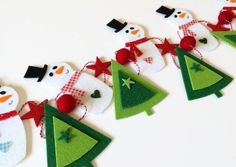 felt snowmen and christmas trees are hanging on the wall in front of a white background