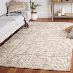 a living room area with a couch, chair and rug on the hardwood flooring