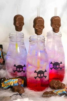 three jars filled with candy and skulls sitting on top of some white fluffyy material