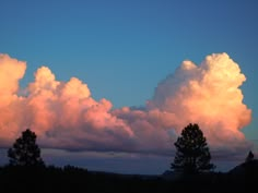 the sky is filled with pink clouds as the sun sets in the distance behind some trees