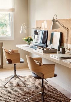 a desk with two chairs and a computer on top of it in front of a window