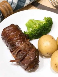 a white plate topped with meat, potatoes and broccoli next to a fork