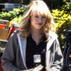 a woman standing in front of a microphone with her hands on her hips and looking at the camera