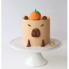 a cake with an orange on top is sitting on a white plate in front of a white background