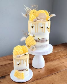 two tiered cake with honeycombs and bees on top sitting on a wooden table