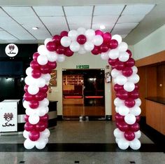 an archway decorated with red and white balloons