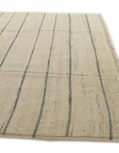 a beige rug with blue stripes on the top and bottom, in front of a white background