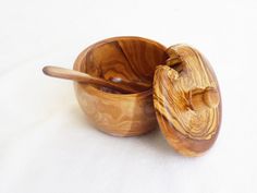 two wooden bowls with spoons in them on a white surface