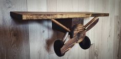 a wooden airplane shaped shelf with wheels on the bottom and wood paneled wall behind it