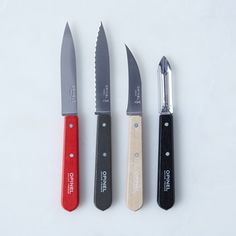 three knives are lined up next to each other on a white surface with one knife in the middle