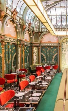 a long table with red chairs and plates on it in a room that looks like a palace