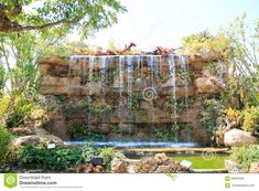 a waterfall in the middle of a garden with lots of plants growing on top of it