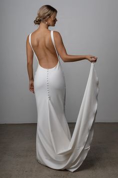 a woman in a white dress with her back turned to the camera and holding something