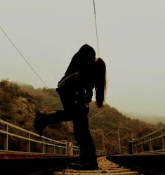 a woman standing on top of train tracks with her hair blowing in the wind,