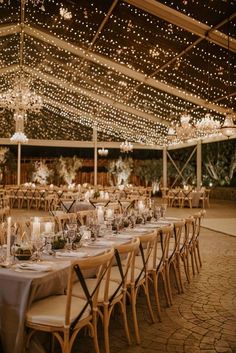 an outdoor tent with tables and chairs covered in lights