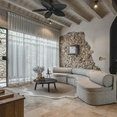 a living room with stone wall and ceiling fan