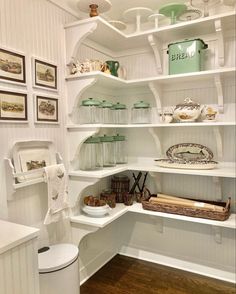 a kitchen with white shelves and pictures on the wall