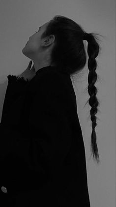 a woman with long hair standing in front of a wall and looking up at the sky