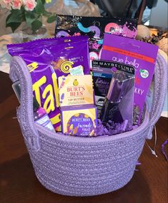 a purple basket filled with lots of different types of snacks and candy bars on top of a wooden table