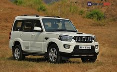 a white suv parked on top of a dry grass field