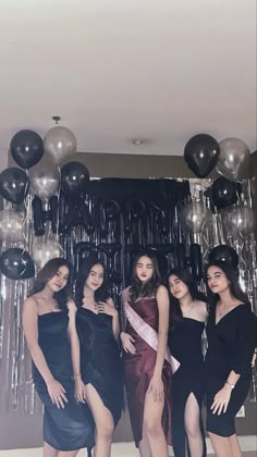 four women posing for a photo in front of balloons